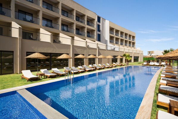 A hotel with a swimming pool, sun loungers, and umbrellas. - Ramada By Wyndham Cesme (Cesme)