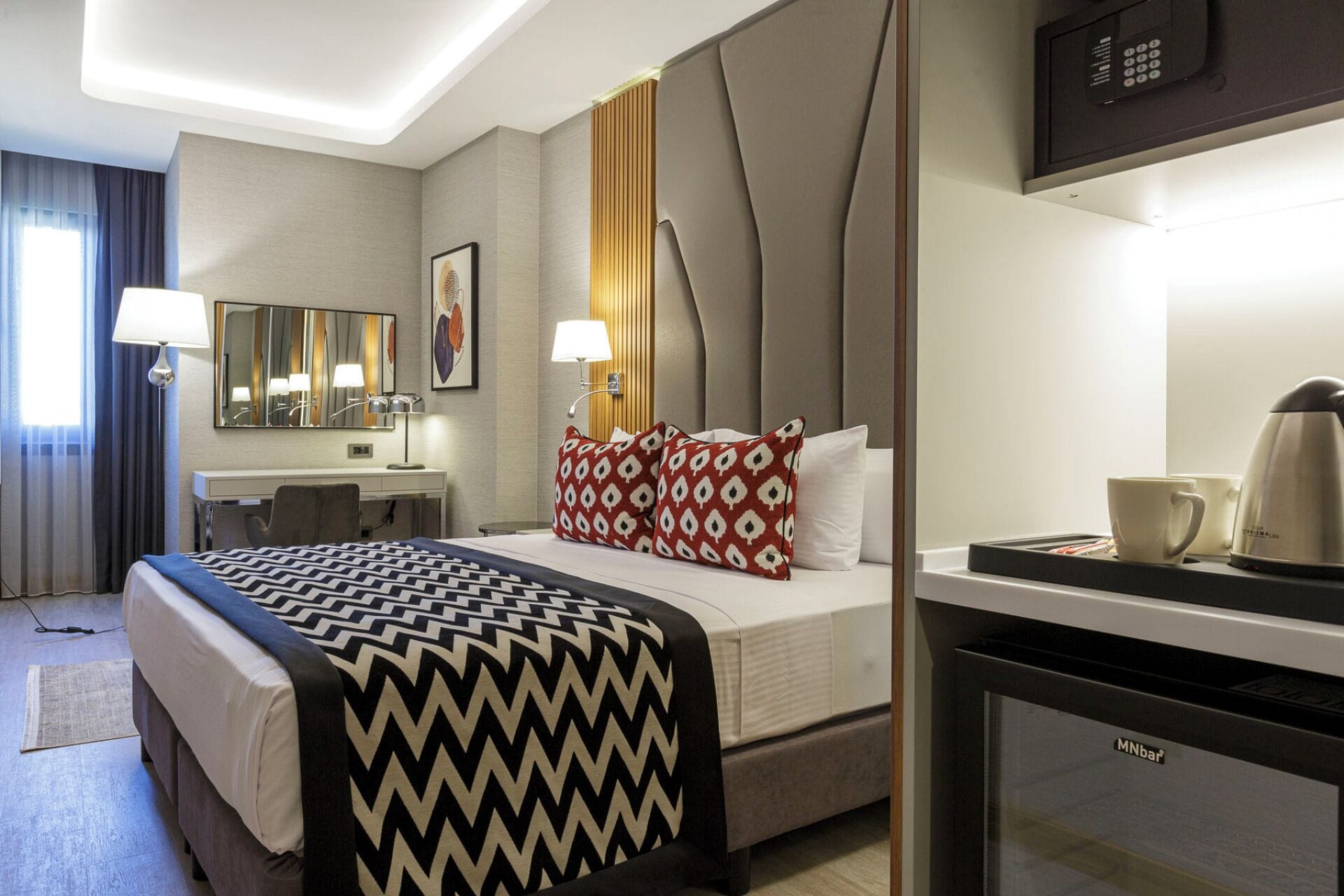 A hotel room with a bed, bedside table, lamp, and a coffee maker.