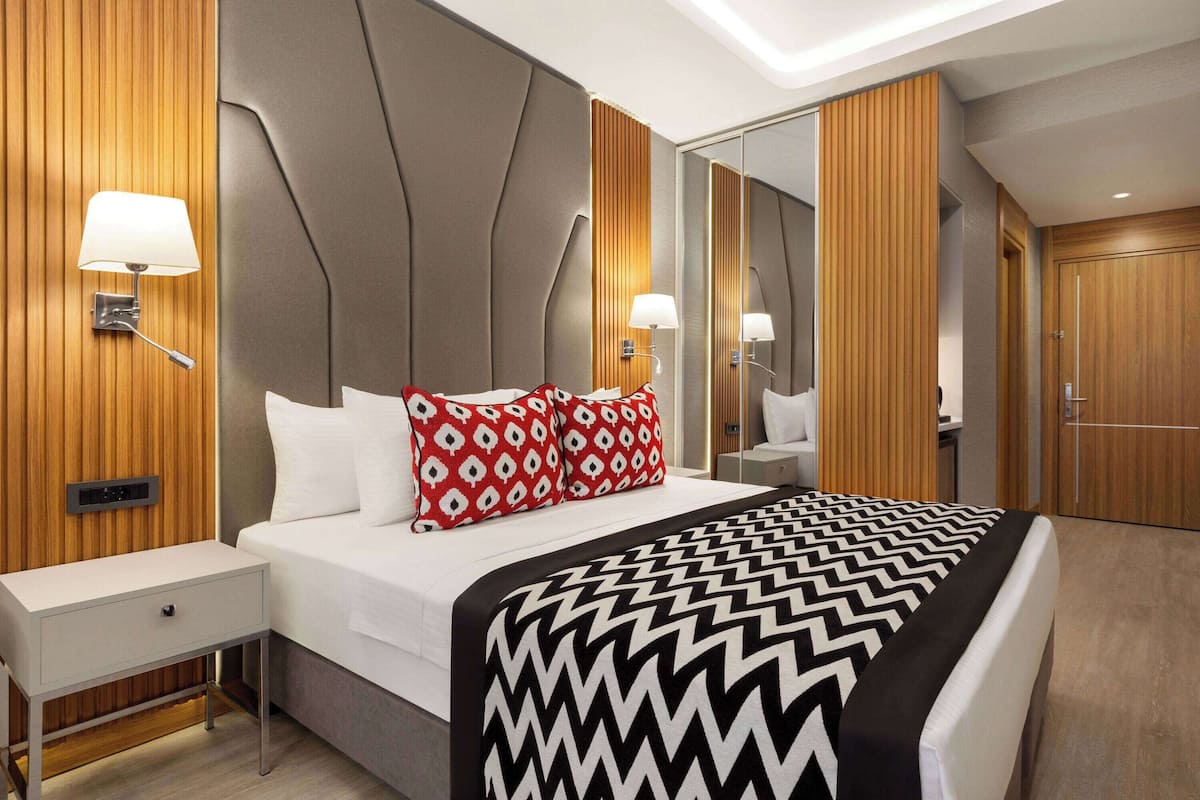 A modern hotel room with a bed, bedside tables, and a large mirror.