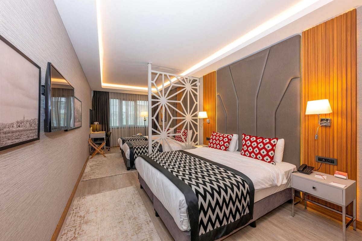 A modern hotel room with a large bed, bedside tables, a desk, and a chair.