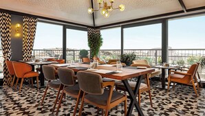 A dining area with a geometric patterned floor, wooden tables, and modern chairs.