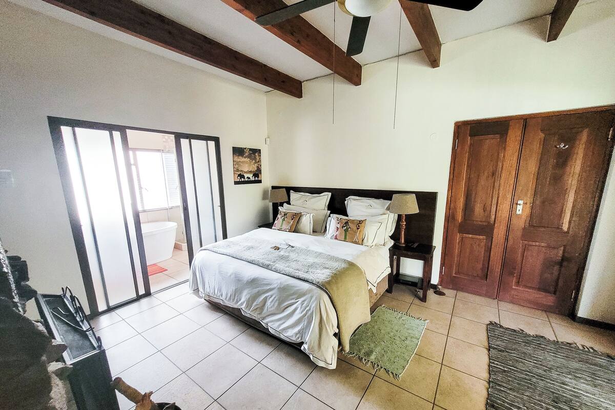 Een slaapkamer met een bed, nachtkastje en houten deur.