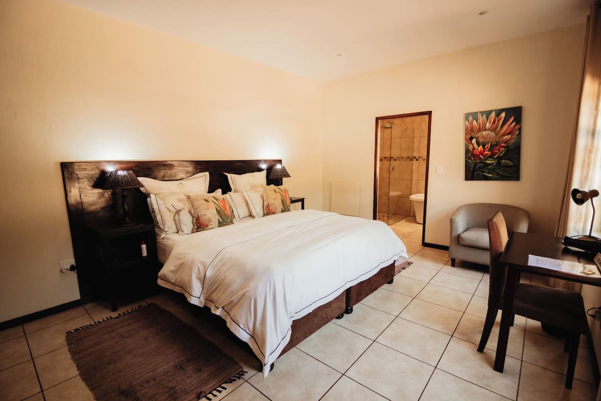 Een slaapkamer met een groot bed, nachtkastjes, een bureau en een stoel.