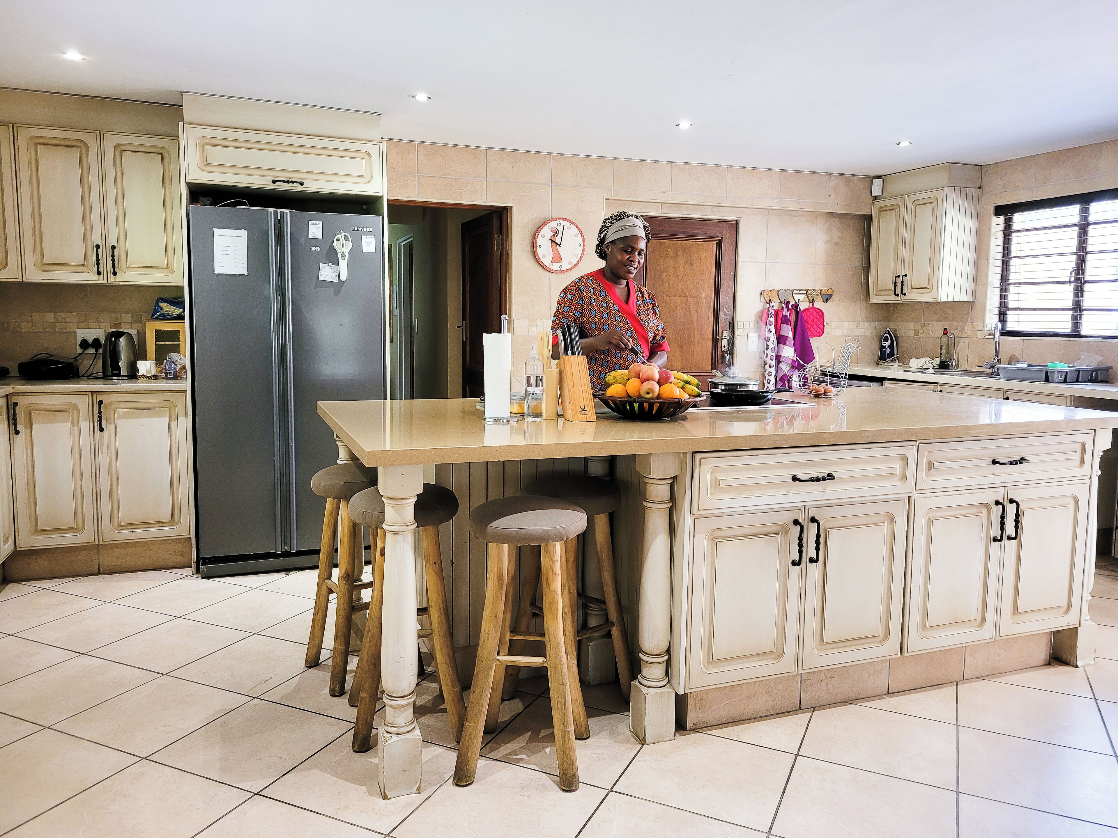 A kitchen with a central island, stools, and a refrigerator.