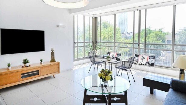Un salon moderne avec une table basse en verre, un canapé et un téléviseur fixé au mur.