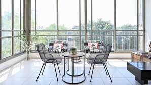 Une pièce spacieuse avec de grandes fenêtres, une table ronde entourée de chaises et une vue sur la verdure.