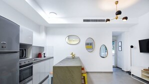 A modern kitchen with stainless steel appliances, a central island with stools, and a flat-screen TV mounted on the wall. - Stylish 2BR in Central Tel Aviv by HolyGuest (Tel Aviv-Yafo)