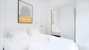 A hotel room with a neatly made bed, a large mirror, and a framed artwork on the wall. - Stylish 2BR in Central Tel Aviv by HolyGuest (Tel Aviv-Yafo)