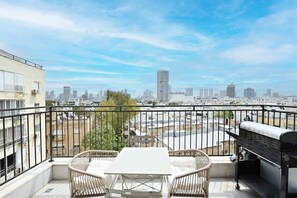 Ein Balkon mit Tisch, Stühlen, Grill und Blick auf die Stadt.
