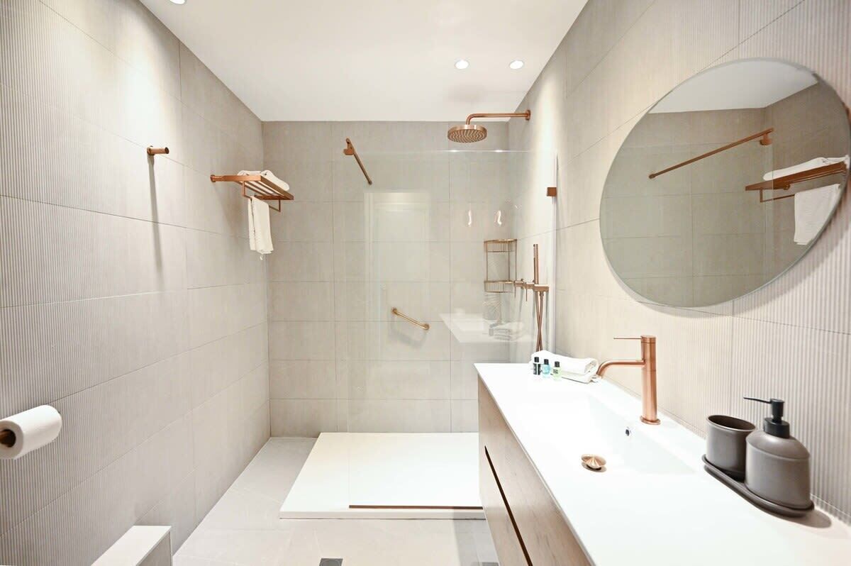 A modern bathroom with a shower, toilet, and sink.