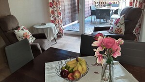 A dining area with a table set for two, featuring a fruit basket and a vase with flowers. - 2 Bedroom Apartment in Haren (Ems) (Haren (Ems))