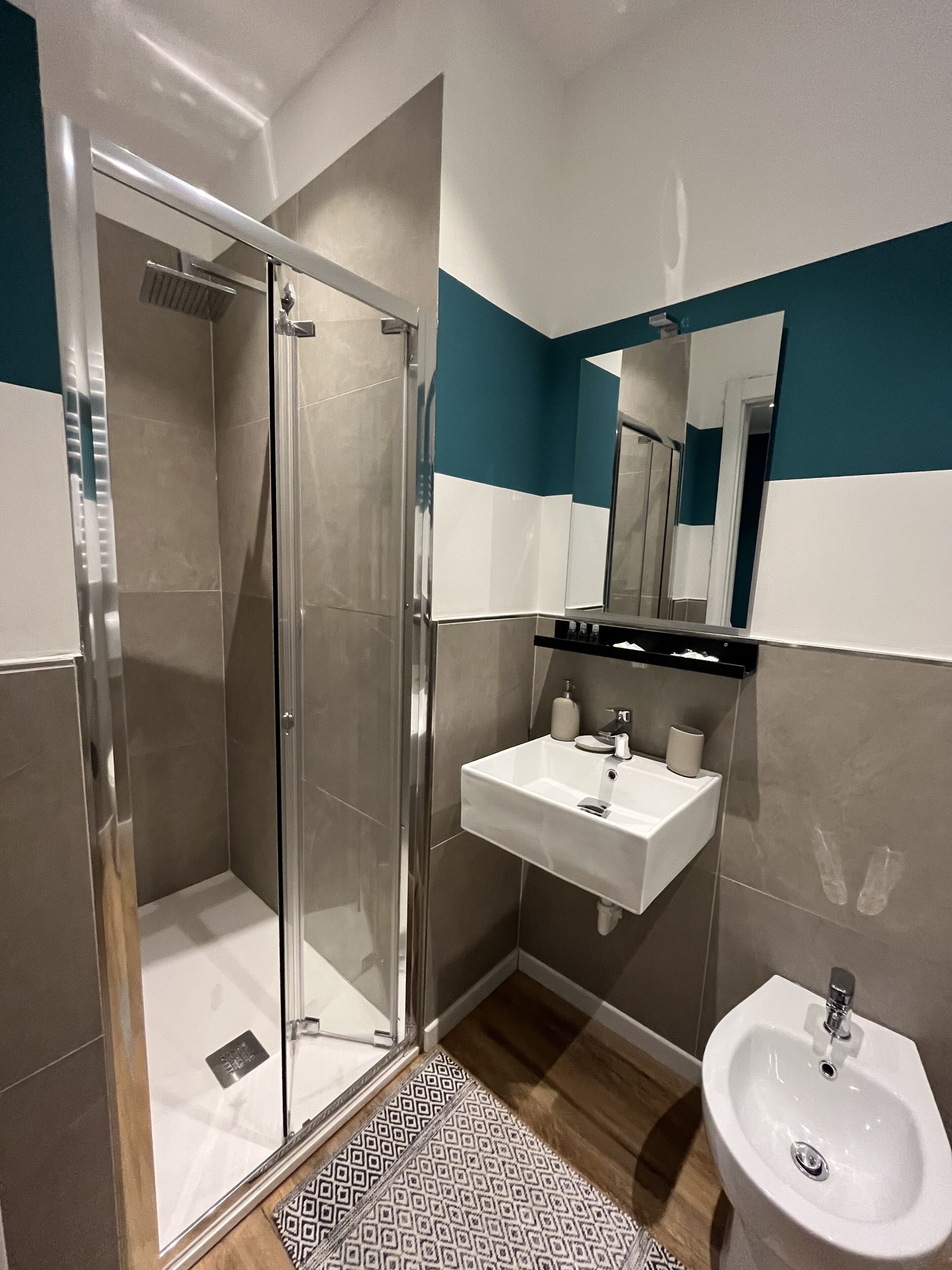 A modern bathroom with a glass shower enclosure, a white sink, and a bidet.