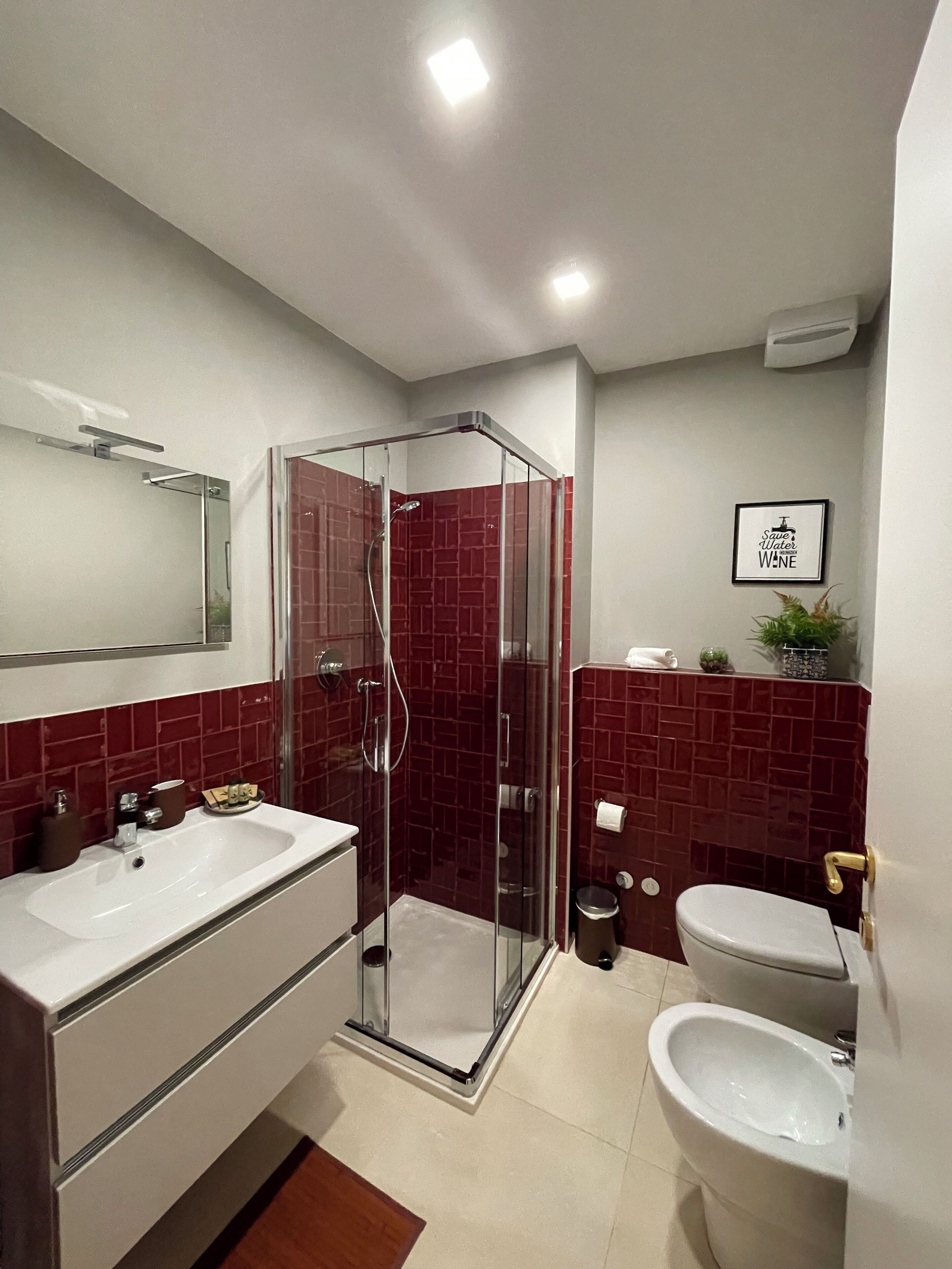 A bathroom with a glass-enclosed shower, a white sink, and a toilet.
