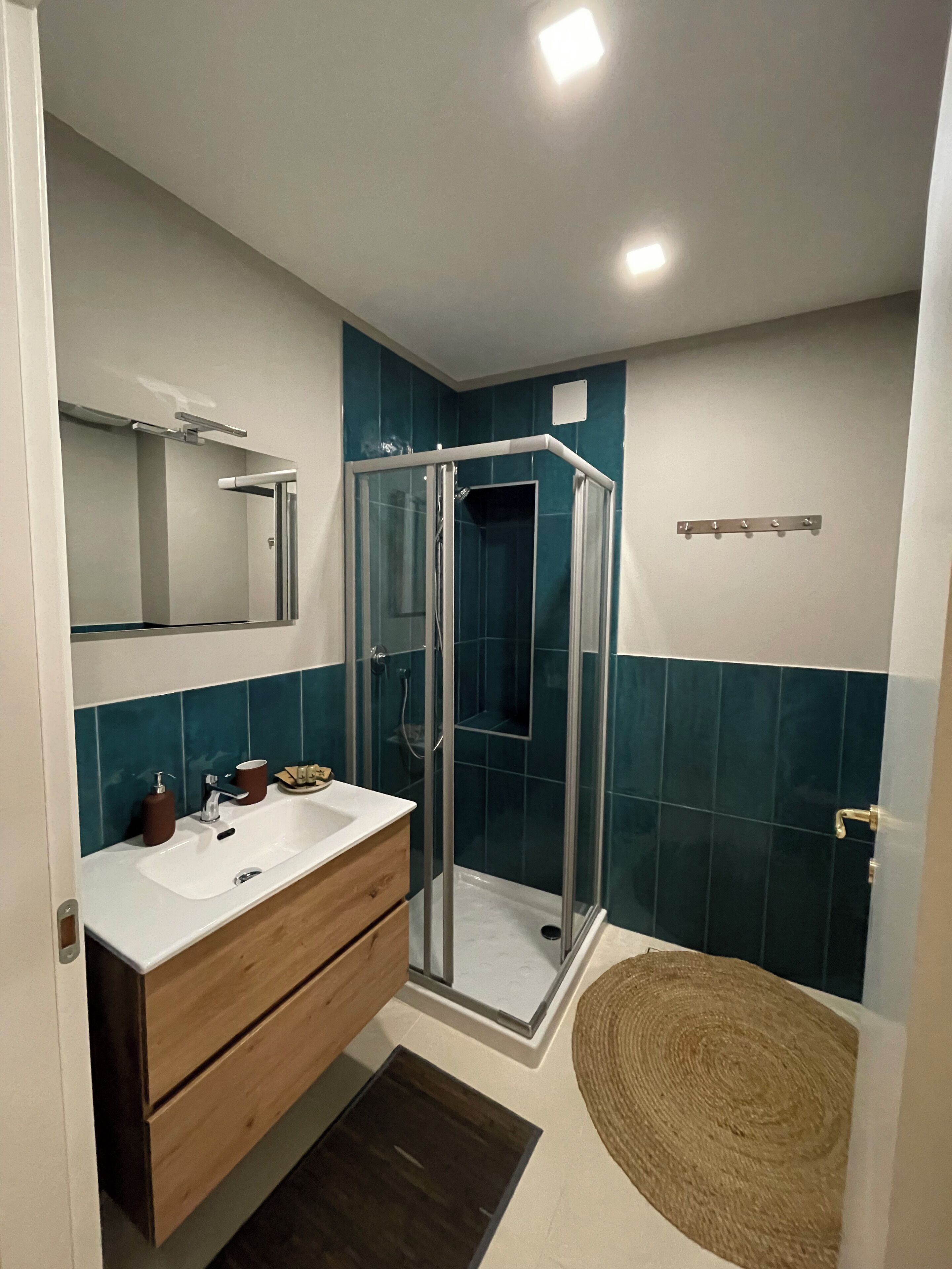 Une salle de bain moderne avec une douche à parois de verre, un meuble-lavabo en bois et un grand miroir.