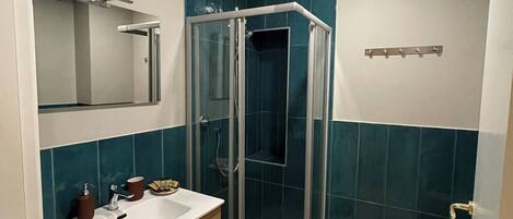Un baño moderno con ducha de vidrio, tocador de madera y un espejo grande.
