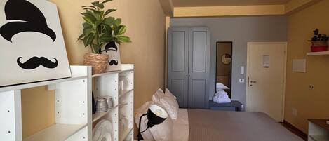 A compact room with a bed, a desk, and a chair. There is a potted plant on the desk.