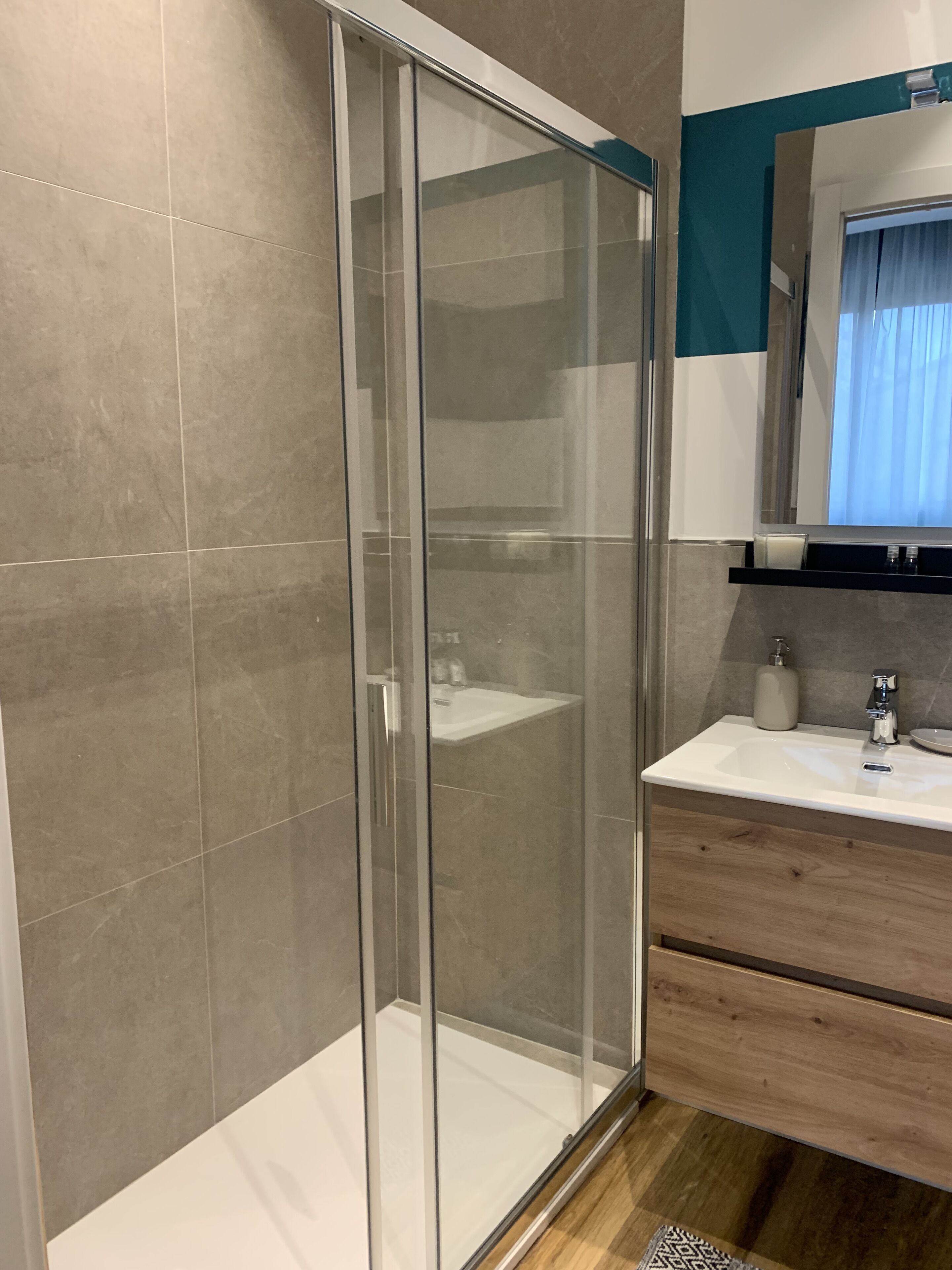 Un bagno moderno con box doccia in vetro, lavandino e specchio sopra.