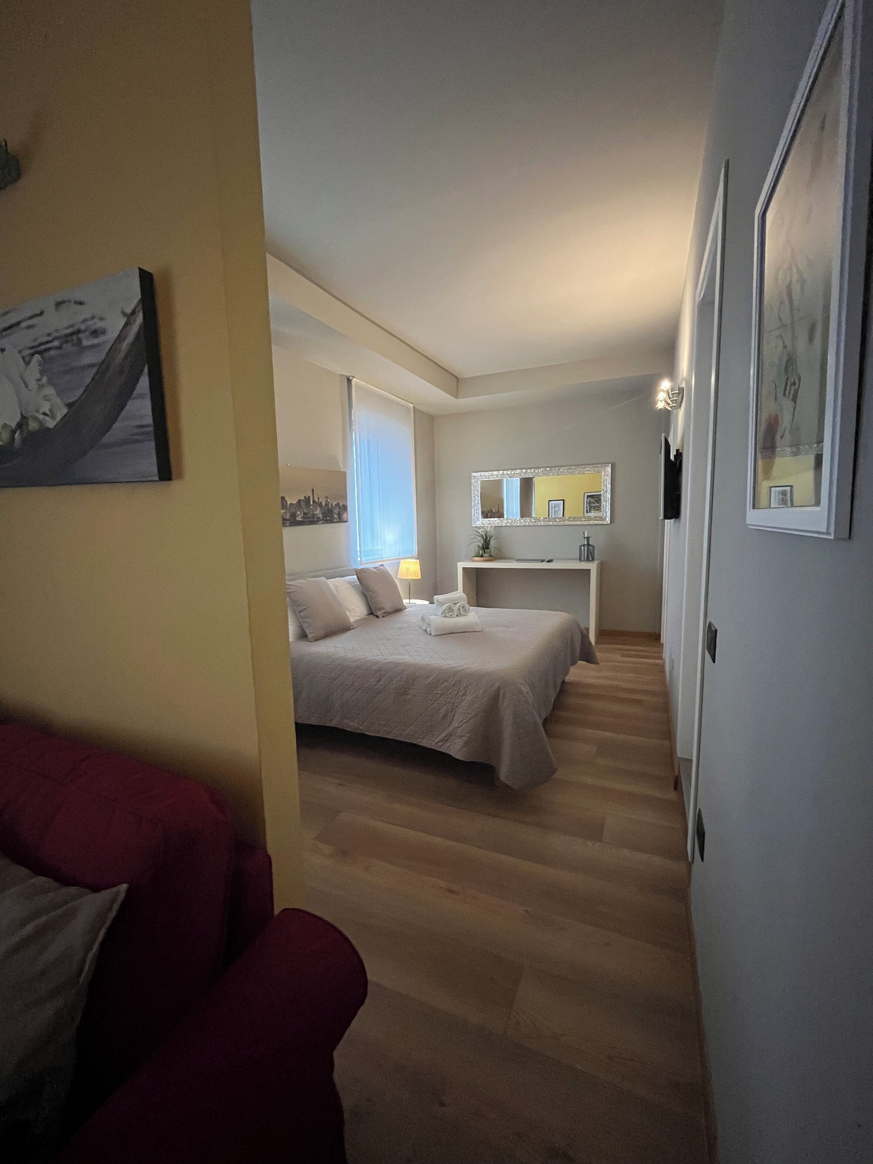 Ein Schlafzimmer mit einem Bett, einem Nachttisch, einem Spiegel und einem Fenster mit Jalousien.