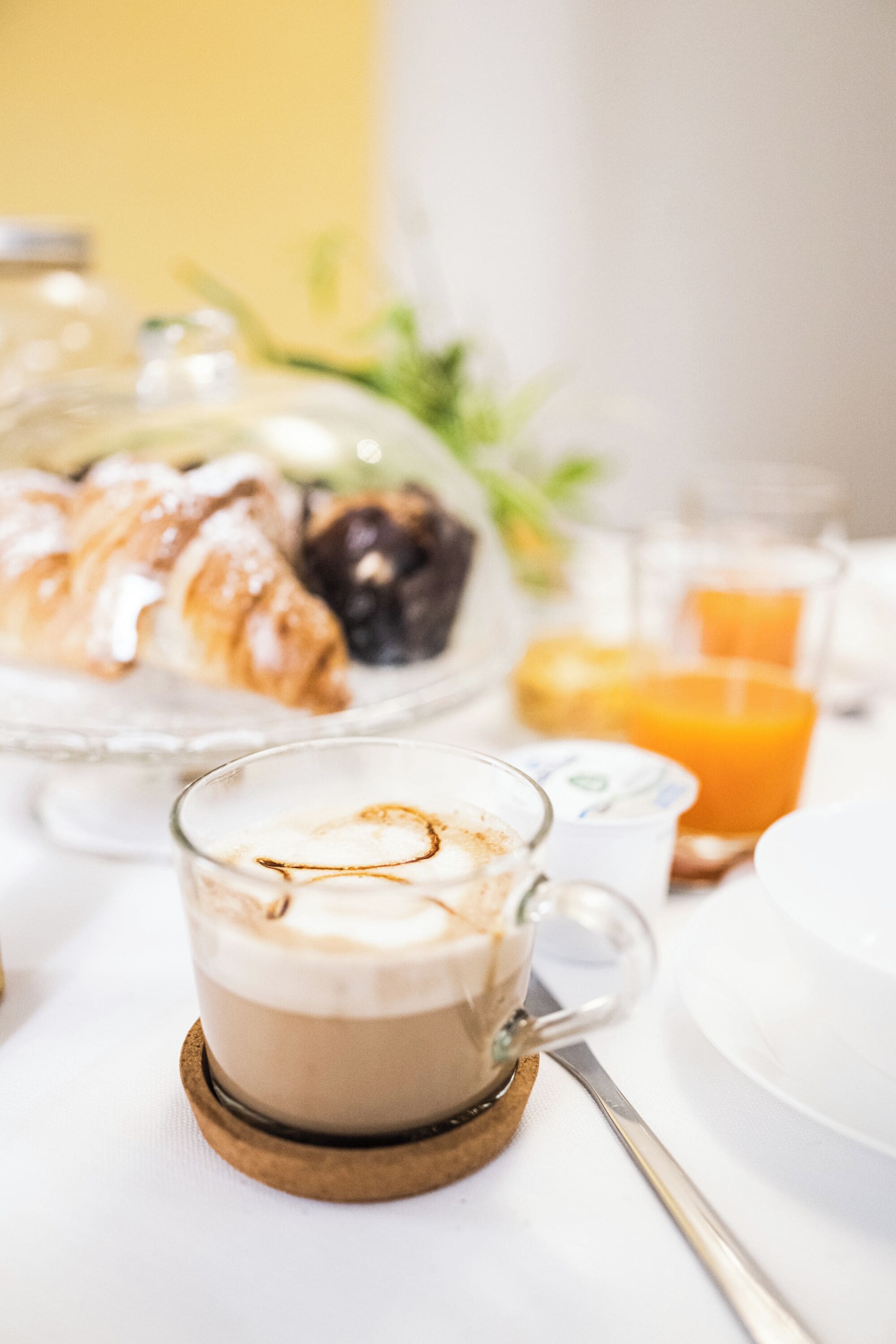 En frukostuppsättning med en croissant, ett glas apelsinjuice och en kopp kaffe på ett bord.