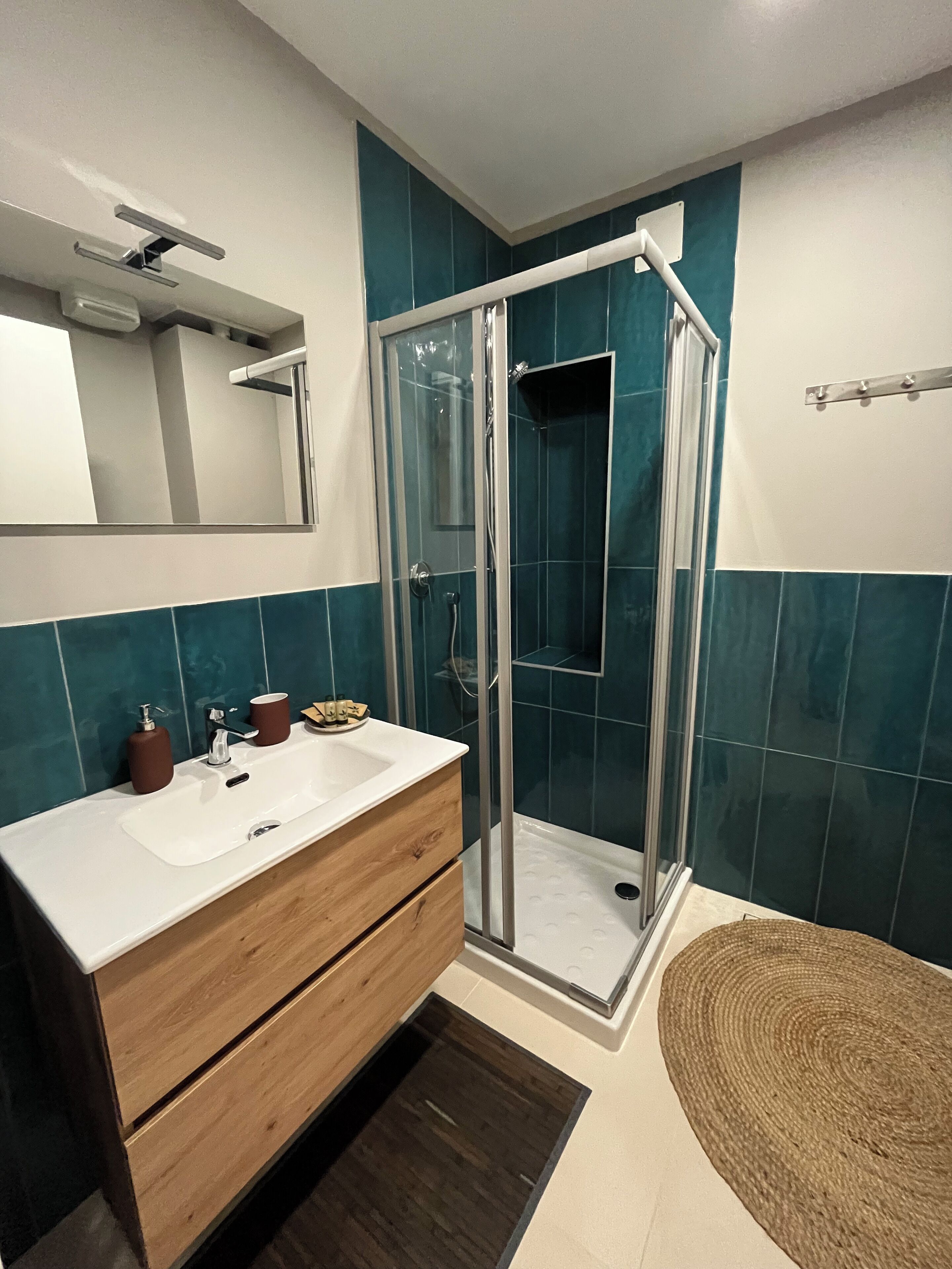 A modern bathroom with a glass-enclosed shower, a wooden vanity with a sink, and a mirror above it.