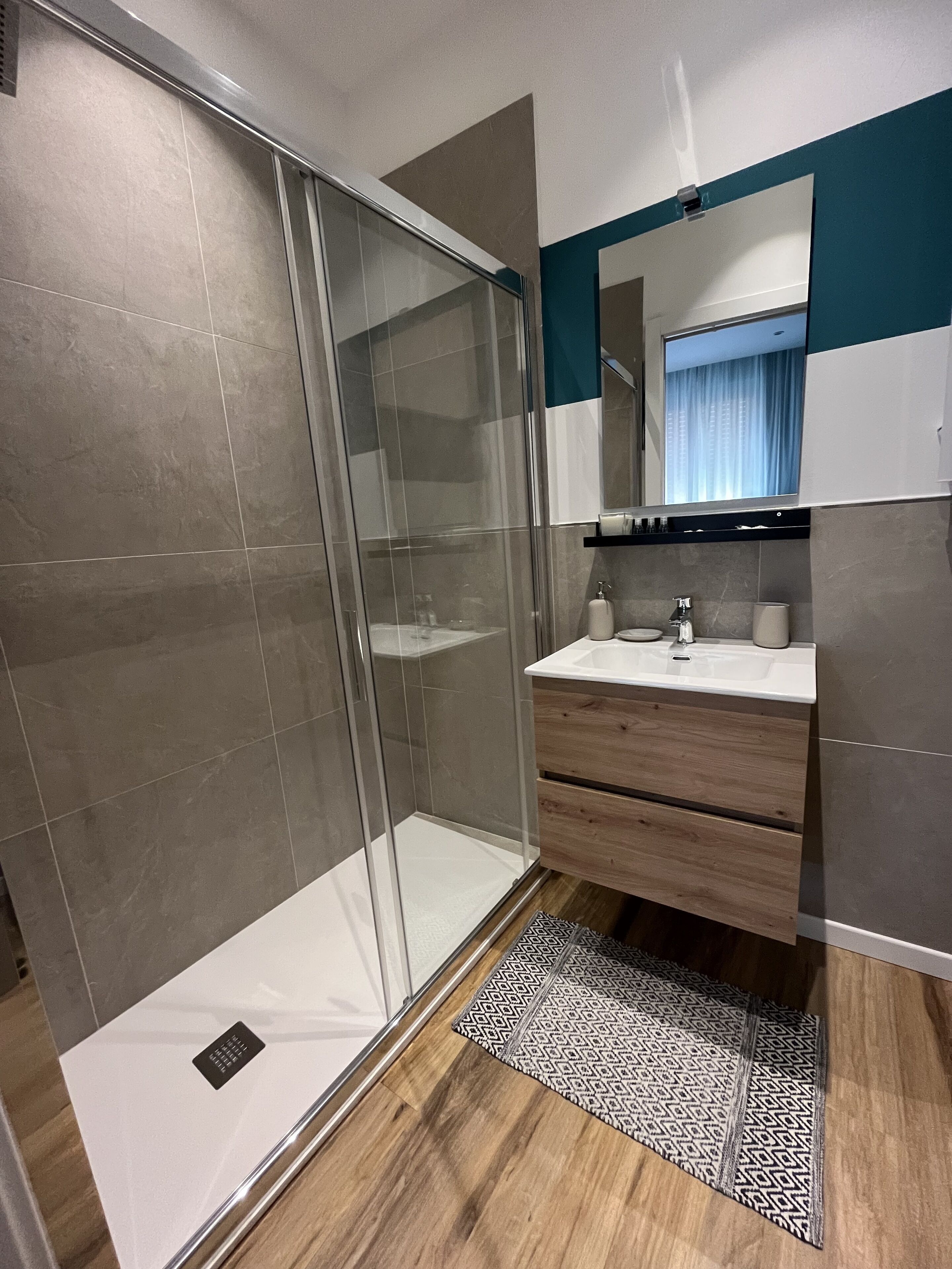 Une salle de bain moderne avec une douche à parois de verre, un meuble-lavabo en bois et un miroir au-dessus du lavabo.