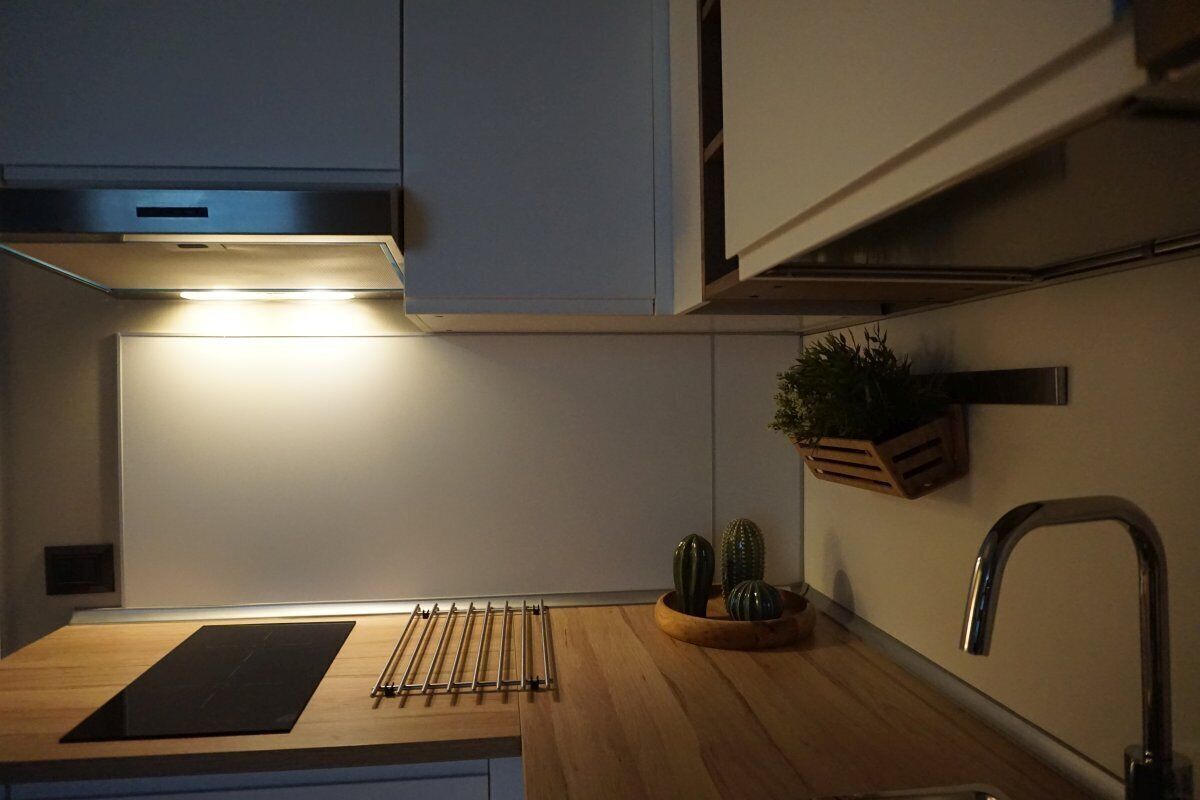 A modern kitchen with a wooden countertop, a built-in stove, and a stainless steel faucet.