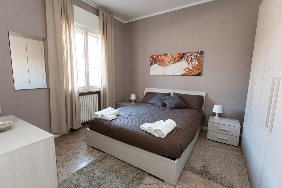 Una camera da letto con un letto grande, un comodino, una cassettiera e una finestra con tende.
