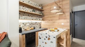 Cozinha moderna com prateleiras de madeira, mesa de jantar e luminária pendente.