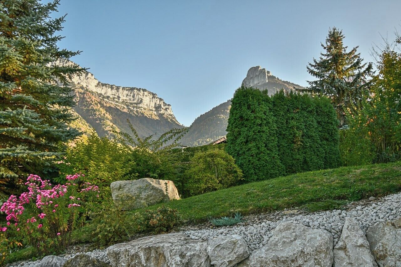 Paisagem montanhosa com céu claro, vegetação exuberante e uma formação rochosa imponente.