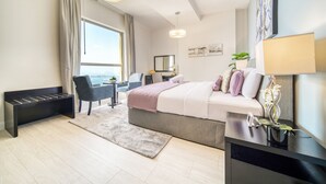 Ein modernes Hotelzimmer mit einem großen Bett, einem Schreibtisch, einem Sessel, einem kleinen Tisch mit Pflanze und Blick auf die Stadt.