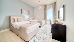 A hotel room with a large bed, a smaller bed, a desk with a TV, and a view of the city.