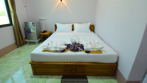 A neatly made bed with a decorative pillow arrangement, a bedside table with a phone, and a wall-mounted light fixture. - Royal Palace Hotel - Magway (Magwe)