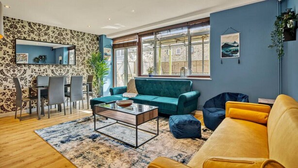 Een moderne woonkamer met een bank, fauteuils, een salontafel en een eethoek met stoelen en een tafel.