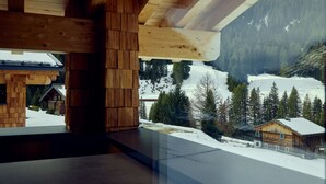 Een houten hutje met uitzicht op een besneeuwd berglandschap.