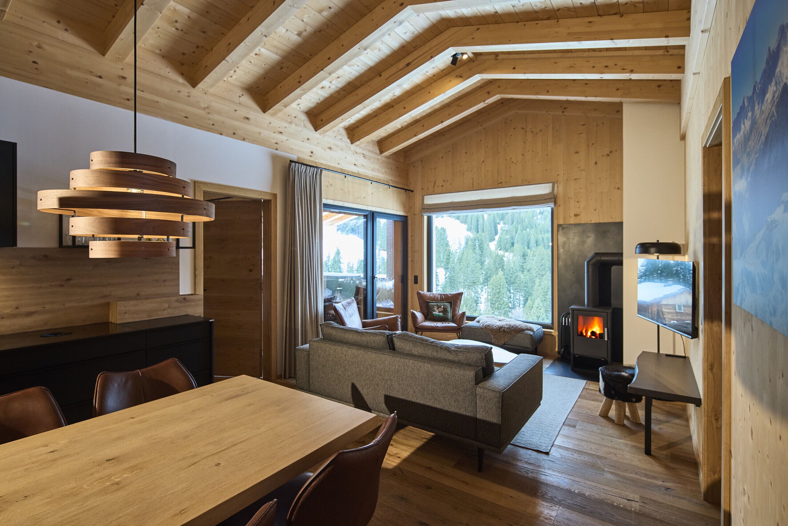 A modern interior with a wooden ceiling, a dining area, a sofa, and a fireplace.