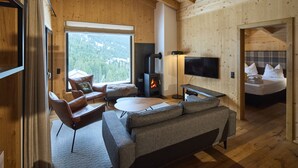 Een gezellig interieur van een blokhut met een open haard, een bank, een televisie en een bed.