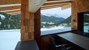 Een houten interieur met uitzicht op besneeuwde bergen en een dorp.