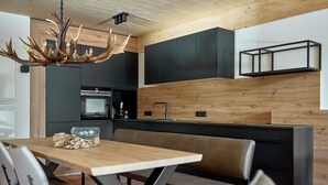 A modern kitchen with a wooden ceiling, black cabinets, and a central island with seating.