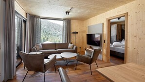 A modern interior with a wooden ceiling, a sofa set, a round coffee table, a TV, and a bed in a separate room.