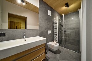 A modern bathroom with a large white sink, wooden vanity, a glass-enclosed shower, and a white toilet. - 5803 Alm-Lodge trais Ski-in-out (Gargellen)