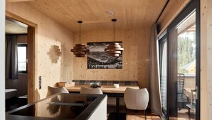 Un interior modern amb parets de fusta, una zona de menjador amb una banca i llums penjants.