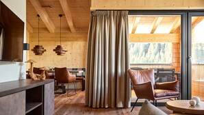 Ein modernes Interieur mit Holzböden, einer Essecke, Ledersesseln und einem großen Fenster mit Vorhängen.