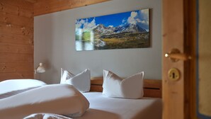 Ett hotellrum med träpanel på väggarna, en säng med vita sängkläder och en tavla med ett bergslandskap på väggen.