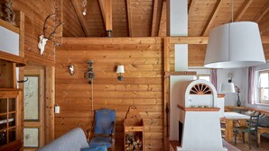 En mysig stuga med träpanel på väggarna, en öppen spis, en soffa och en matplats.