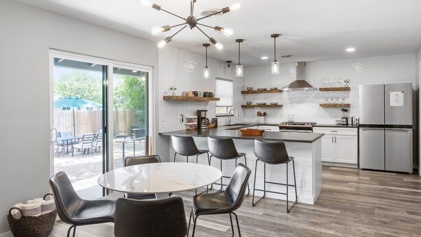 A modern kitchen with a central island, bar stools, and pendant lighting. - Zander Haus 3 Bedroom Home by RedAwning (Fredericksburg)