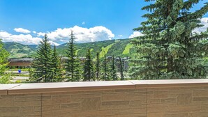 A stone wall with a view of a mountainous landscape, including trees and buildings. - Mtn Views a Short Walk to Lionshead Gondola, SV22A (Vail)
