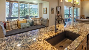 Una cocina con encimera de granito, un lavabo y una ventana con vistas a una terraza.