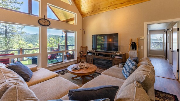 Un salón acogedor con televisor grande, asientos cómodos y vistas al exterior.