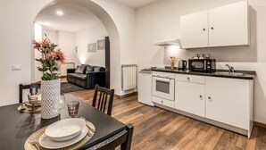 A modern kitchen with white cabinets, a black countertop, and a dining area with a table set for two. - Charming Loft with terrace (Roma)