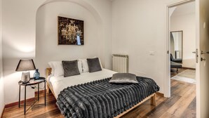 A bedroom with a bed, a nightstand, a radiator, and a door leading to another room. - Charming Loft with terrace (Roma)